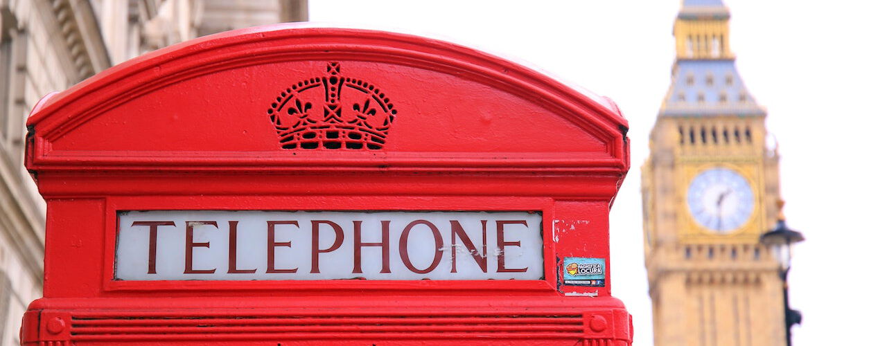 Eine ikonische rote Telefonzelle in London steht im Vordergrund, während der Big Ben im Hintergrund sichtbar ist.