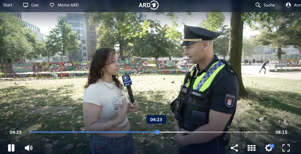 Standbild eines ARD Beitrags, eine Reporterin interviewt einen Polizisten