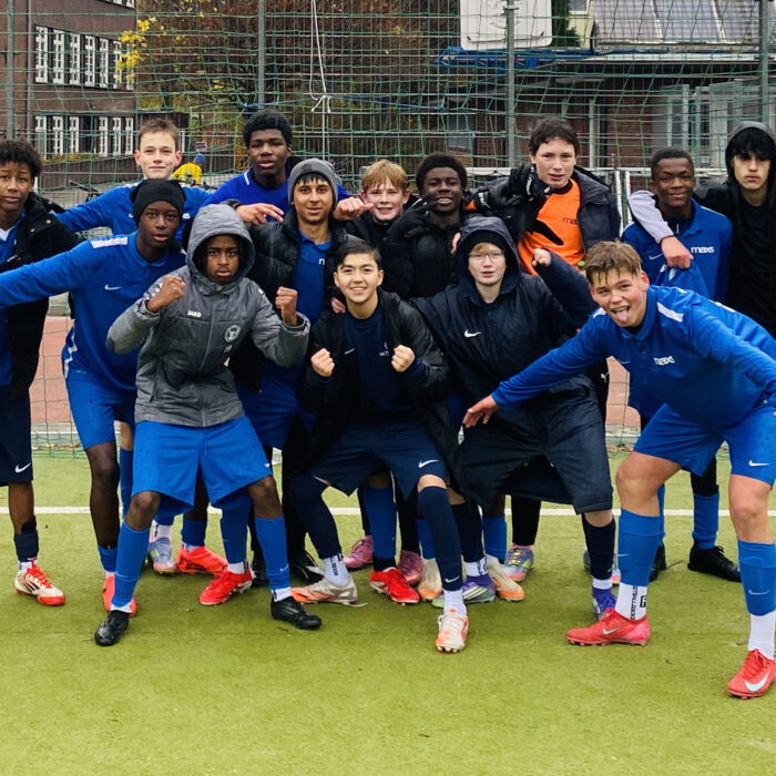 Fußballmannschaft in blauen Trikots jubelt gemeinsam auf dem Platz