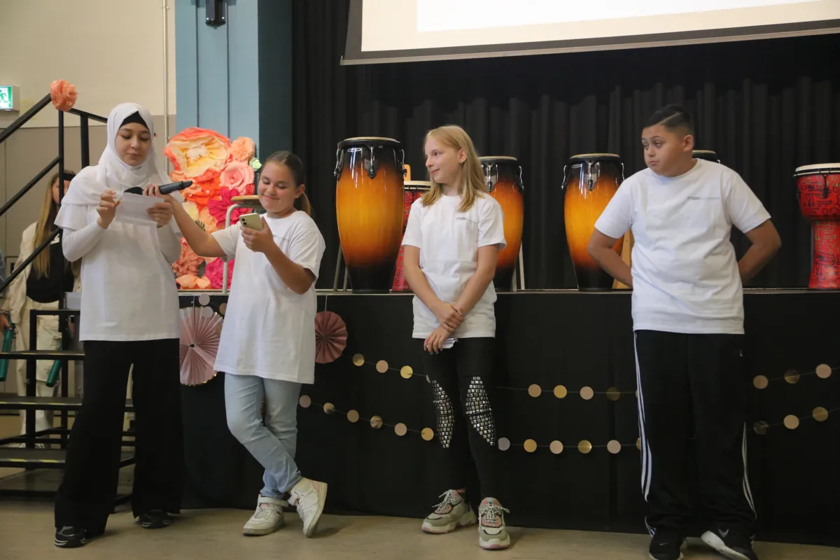 Schülerinnen und Schüler musizieren mit Trommeln auf der Bühne